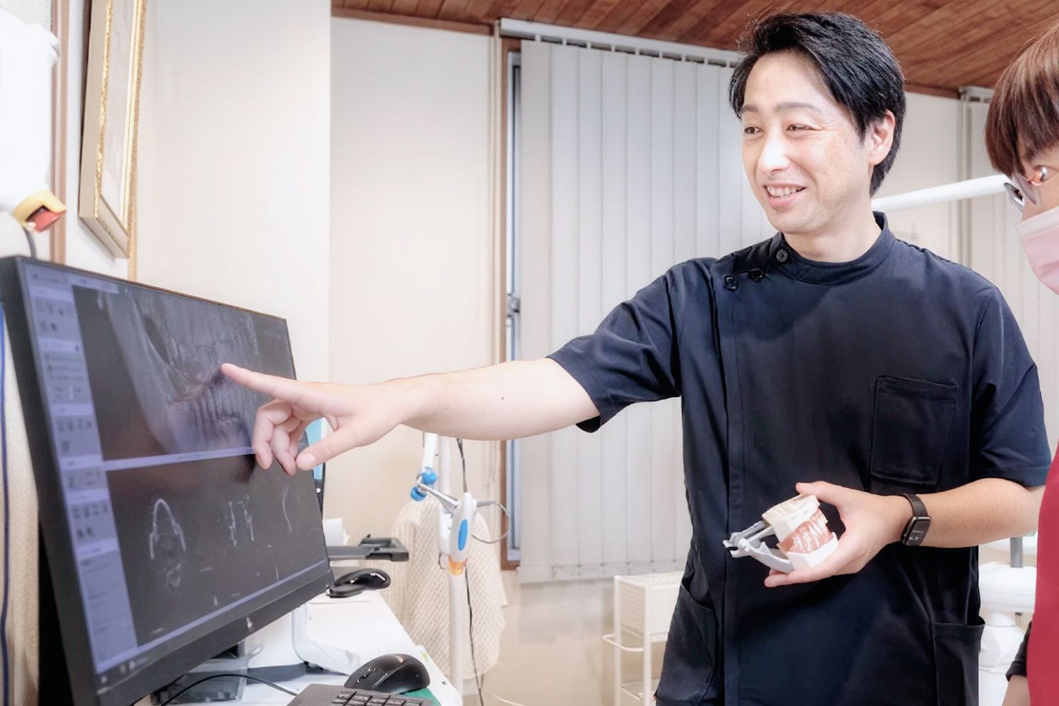 モニターに映した画像を指し示す歯科医師